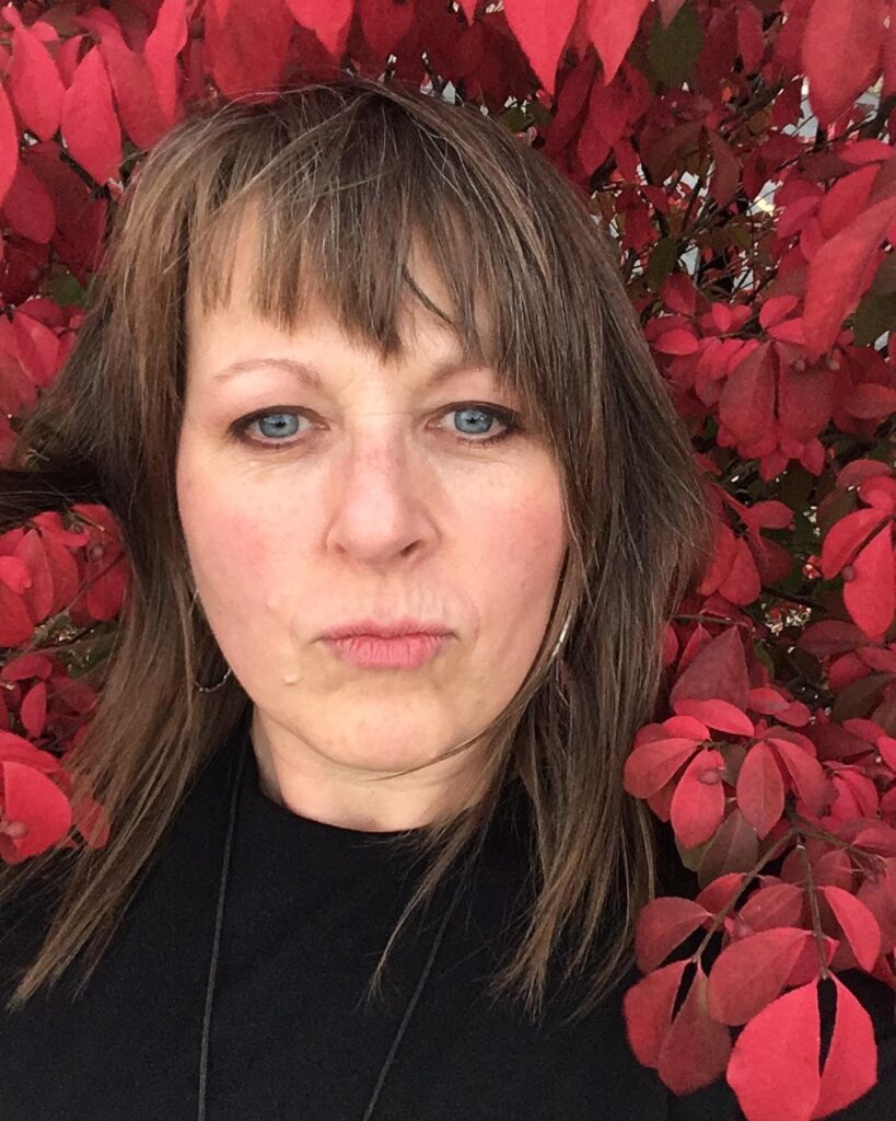 Laura Hugg headshot red flowers serious